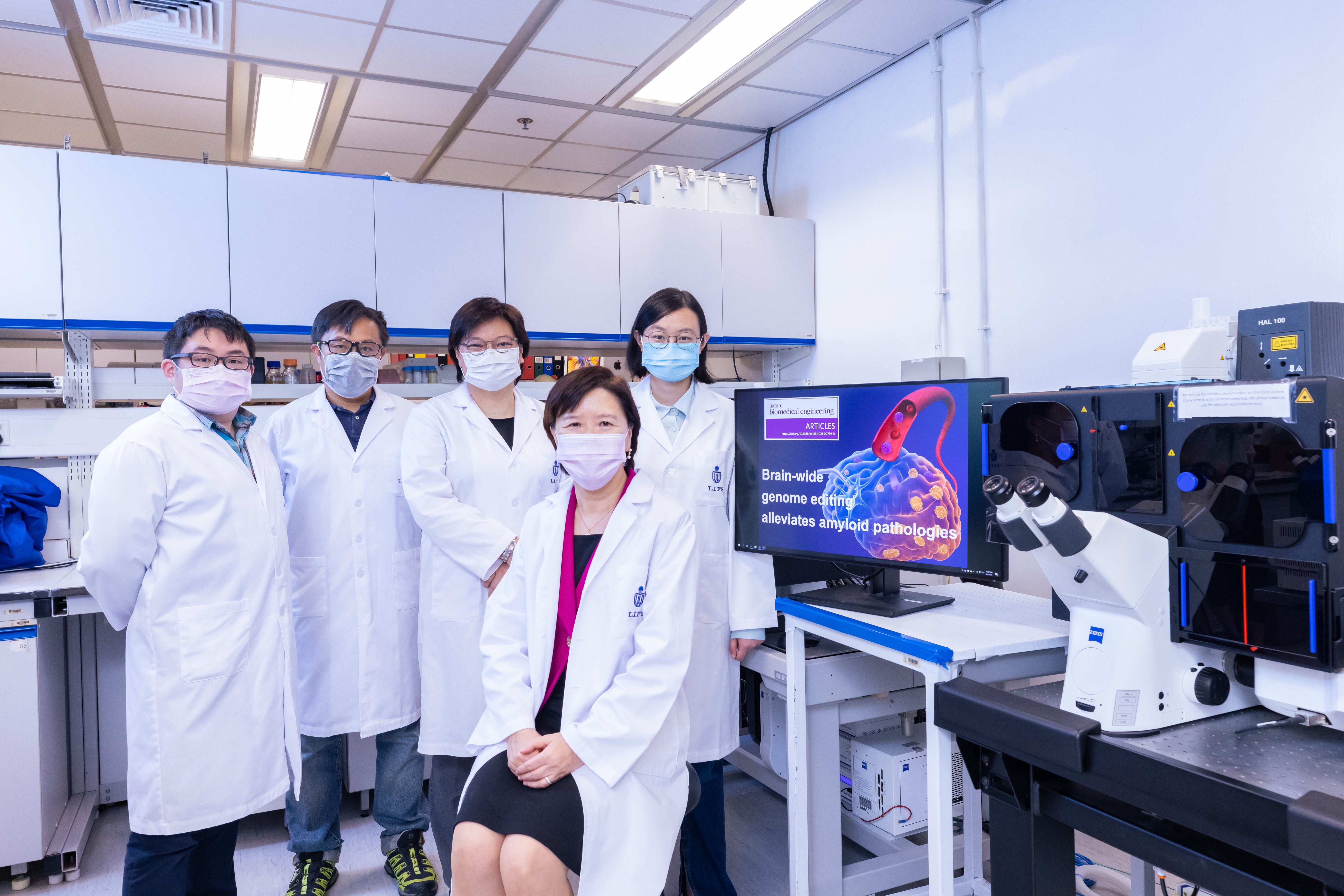 HKUST’s Vice-President for Research and Development, Prof. Nancy Ip (second right) and her research team members – including doctoral student and co-first author of this research paper, Ms. Stephanie DUAN Yangyang (first right) – used the confocal imaging system (pictured) to demonstrate how disruption of a familial Alzheimer’s disease mutation by genome editing strategy reduces disease pathology.